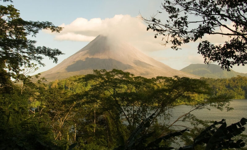 Arenal Volcano seen through the trees and over Lake Arenal.