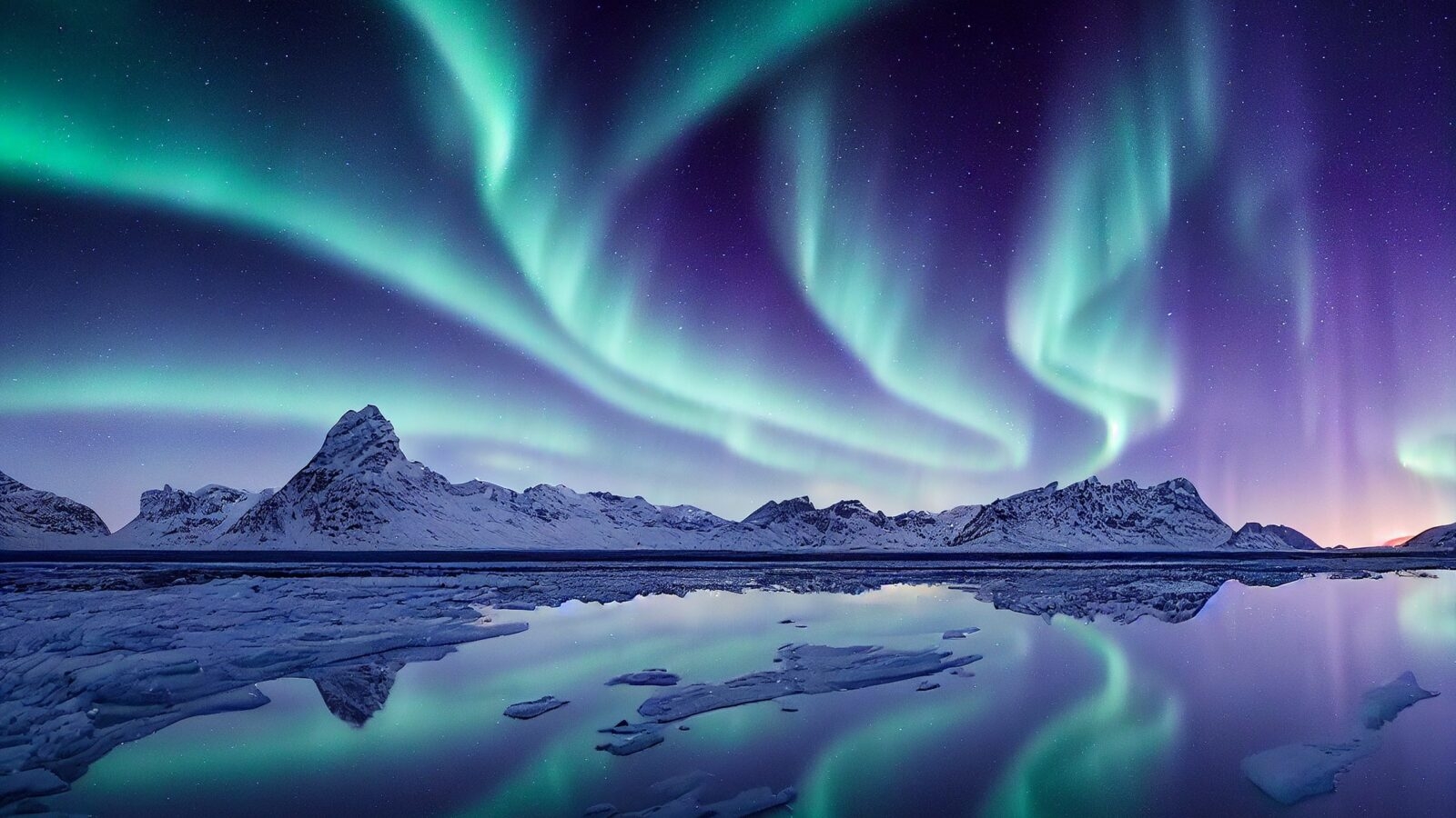 Blue and purple northern lights reflected over a lake