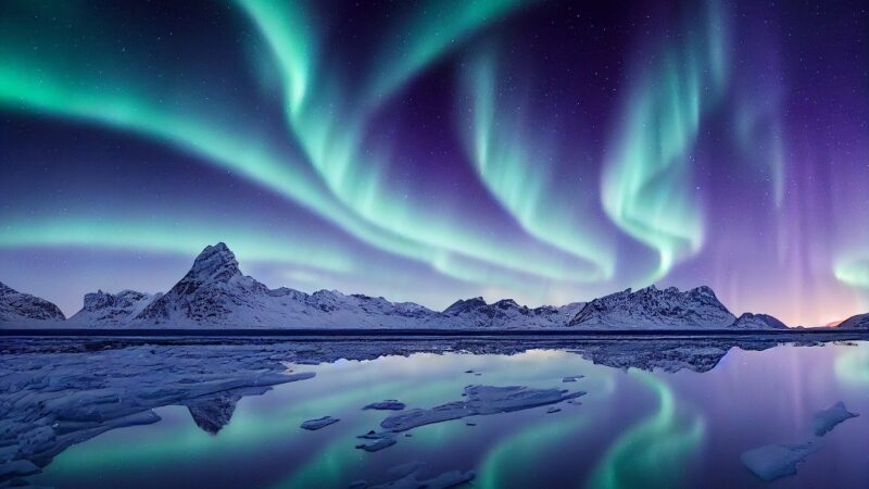 Blue and purple northern lights reflected over a lake
