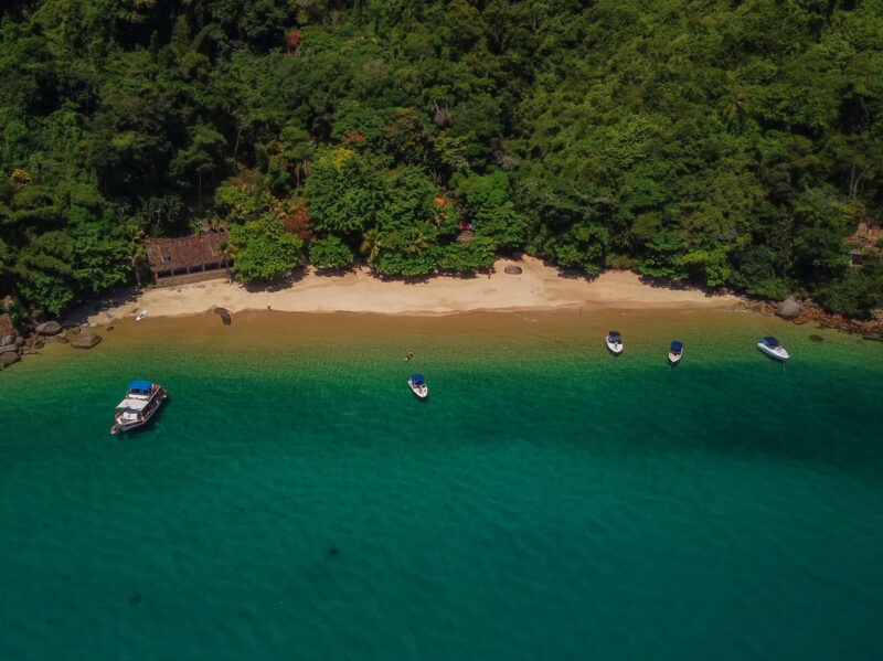 Aerial view of a beach with green ocean and boats near Paraty, Brazil