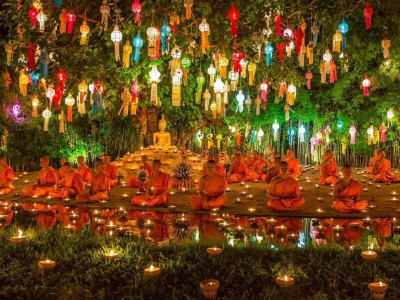 Monks meditating under brightly coloured lanterns at Wat Phan Tao in Thailand