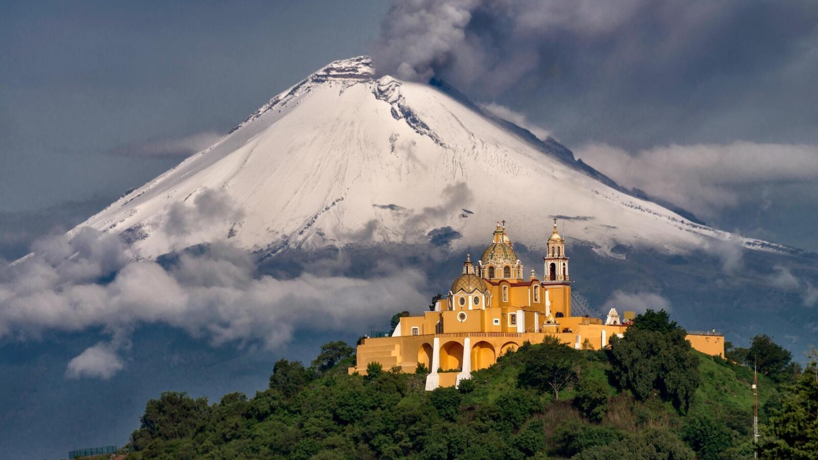 Morning view of church in Puebla, Mexico, and a volcano behind with snow