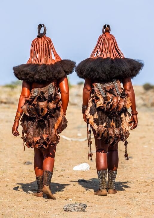 Rear view of two Himba women walking in a desert during positive impact tours.
