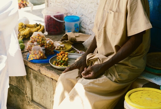 Two Himba people walking side by side, a man sells fruit at a market in Nairobi and a penguin colony on Boulders Beach.