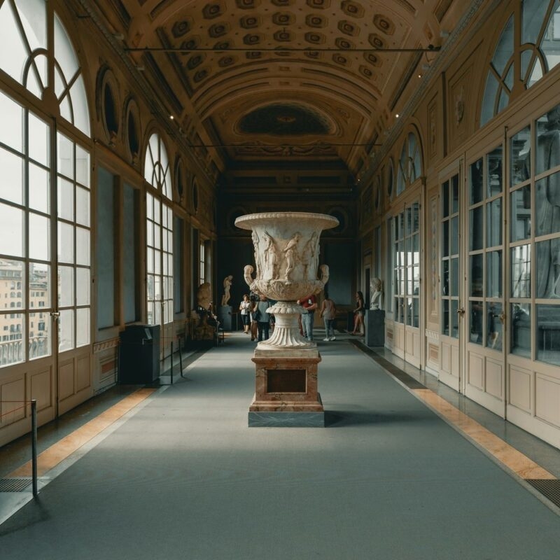 nterior of an ornate museum gallery with a central marble sculpture and large windows for luxury Tuscany tours.