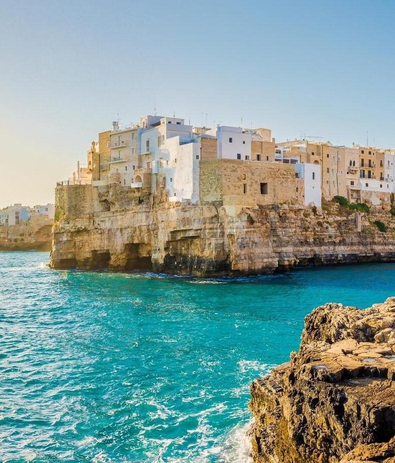 Whitewashed buildings perched above turquoise waters in Polignano a Mare in Puglia and rolling vineyards surrounding the hilltop villages of Piedmont.