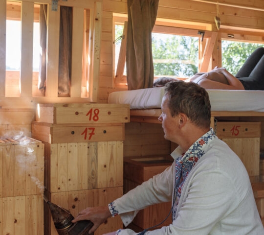 Man smoking bees near woman during apitherapy session