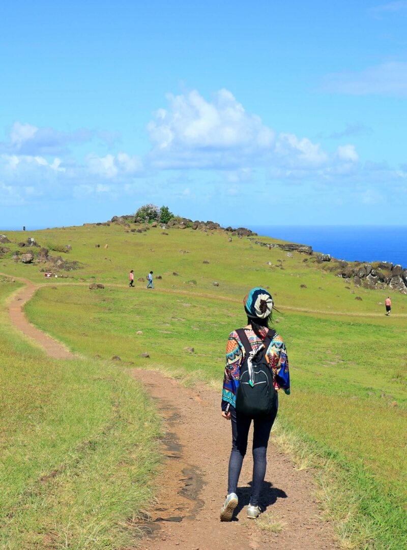 A woman hikes across a grassy hill on Rapa Nui.