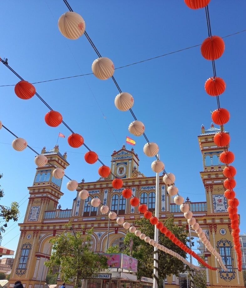 The dramatic cliffs of the Amalfi Coast glowing at dusk in Italy, and lanterns above Seville’s Feria de Abril, a traditional April celebration in Spain.