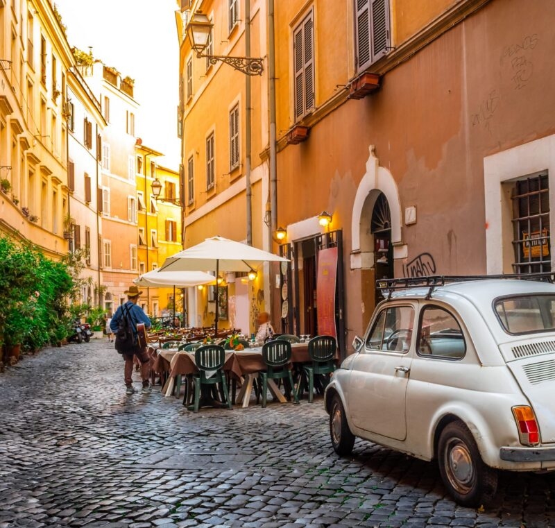 A cozy street in Trastevere in Rome, with a cafe on one side.