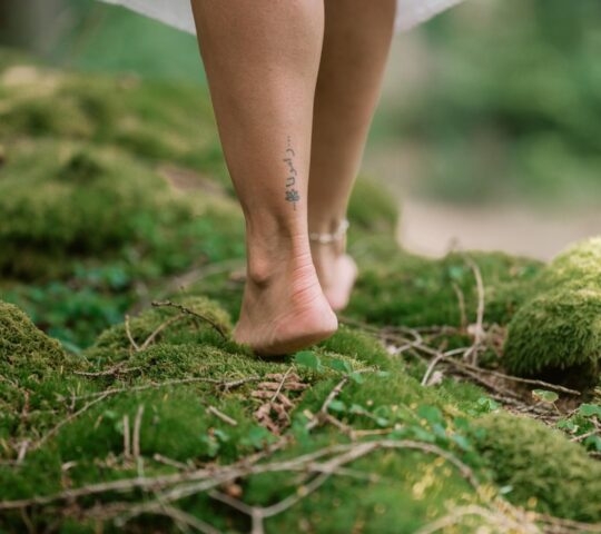a woman joining a barefoot grounding practice in the forest