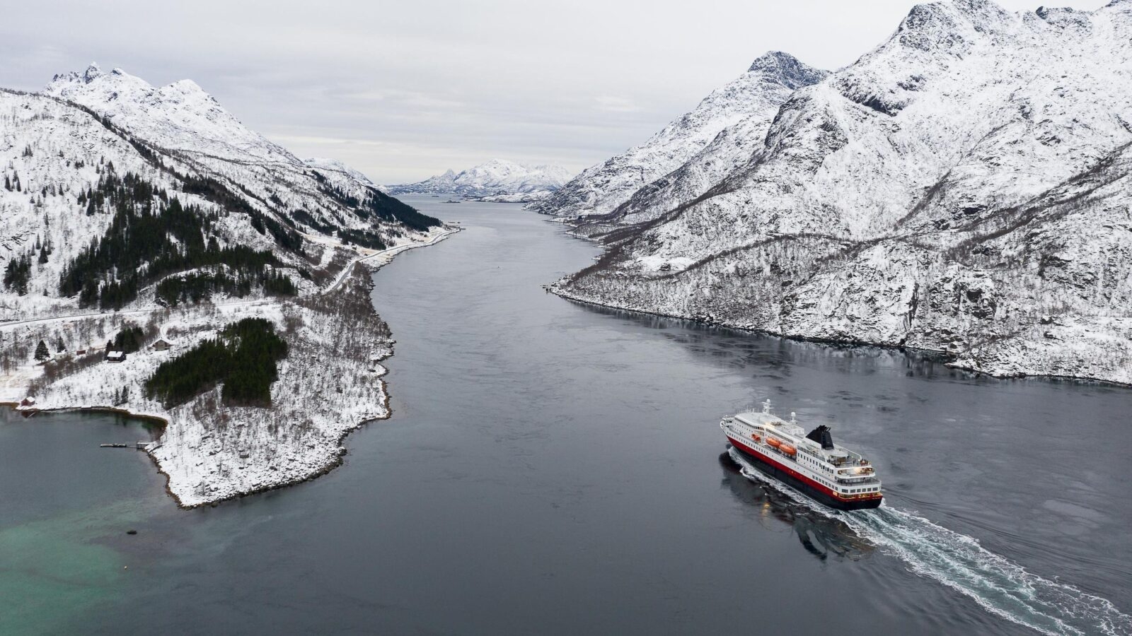 Aerial view of fjord in cold winter weather with Hurtigruten ferry turist boat on the sea.