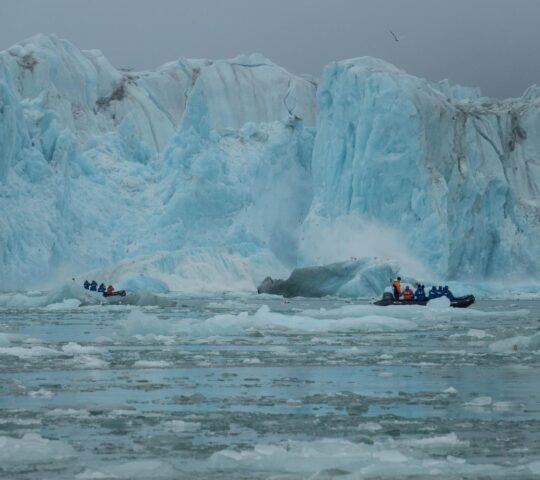 Two Zodiacs cruising in front of a glacier.