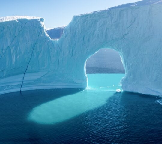Light shining through an archway in an iceberg in the Icefjord off the coast of Greenland