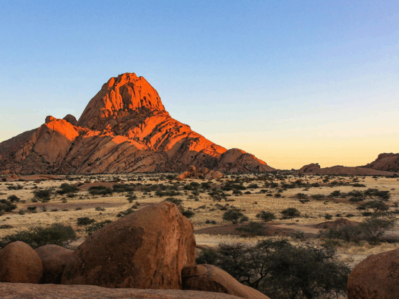 Vistas of the rugged, arid landscape in Damaraland, Namibia, showing red rock formations and dry riverbeds.