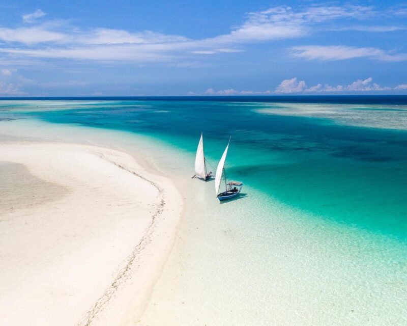 Aerial view of a sandbank with two sailboats in turquoise water in Zanzibar