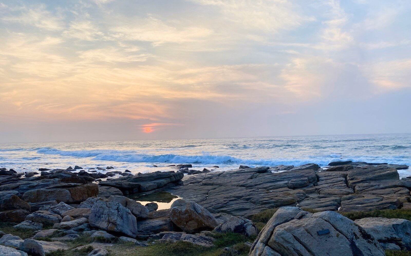 A soft sunset over the rocky shoreline at Uvongo Beach, on South Africa’s subtropical KwaZulu-Natal coast.
