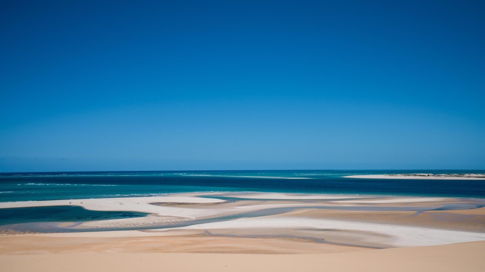 Wide view of sandbars and turquoise ocean water under a clear blue sky in the Bazaruto Archipelago, Mozambique.
