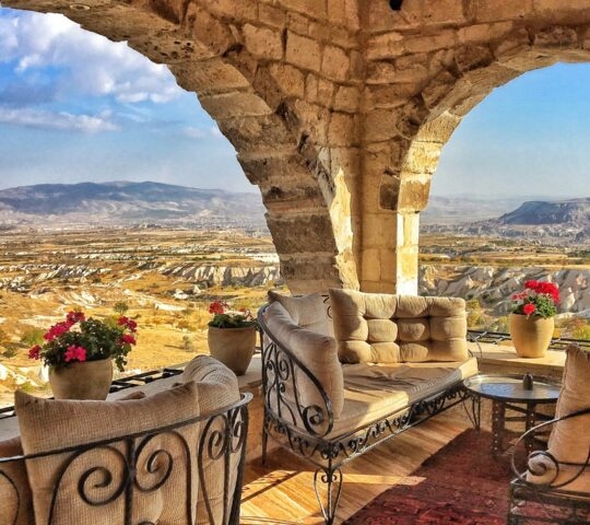 Stone arch terrace with plush seating and flowers overlooking the valley at the Museum Hotel in Turkey.