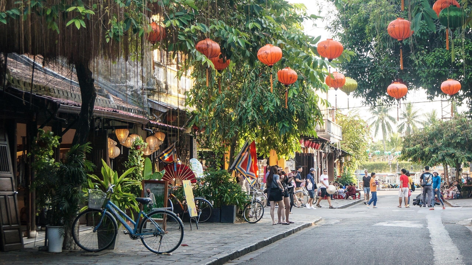 A picturesque street in Hoi An lined with traditional hanging lanterns and historic yellow buildings.