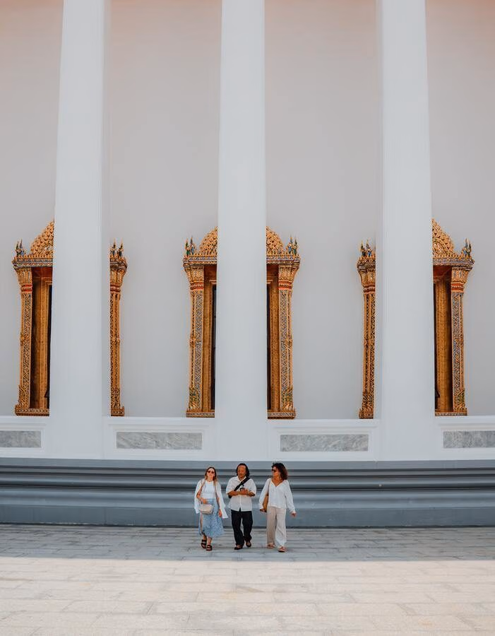 A guide walks with two guests on a Bangkok temple tour.