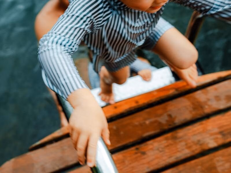 A happy child climbs out of a swimming pool in Thailand.