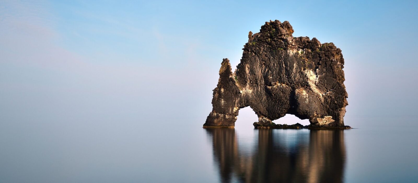 Hvítserkur rock formation rising from the glassy water in northern Iceland