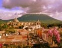 Aerial view of the city of Antigua in Guatemala, framed by pink spring flowers and dramatic mountains