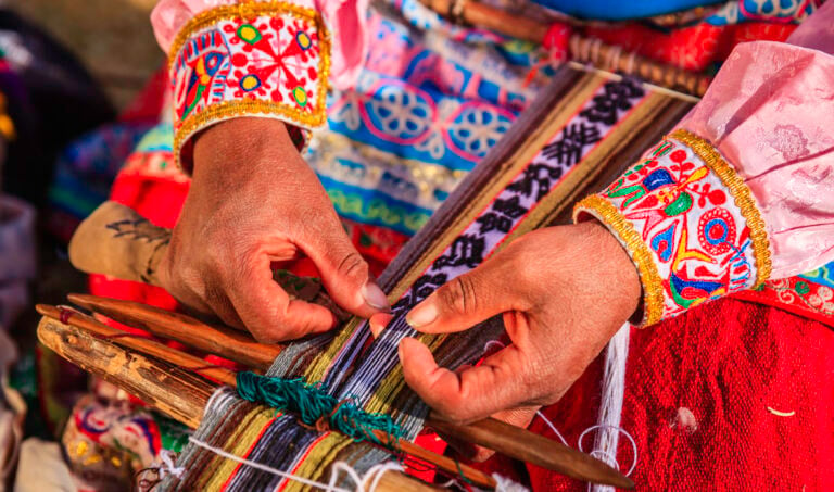 A woman's hand weaving traditional, colourful wool fabric in Peru