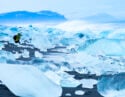 Traveller photographing broken ice which has washed up on the shore of Jokulsarlon Ice Beach, Iceland