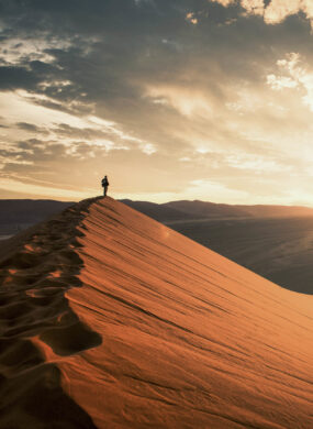 Dramatic sunrise in the Namibian desert with person standing and overlooking the great plains