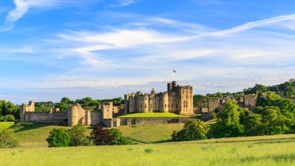 Alnwick Castle in England - a large fortified castle building with a wall around the outside