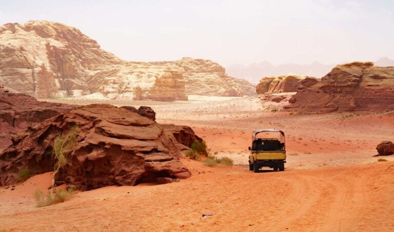 Adventures safari jeep car in Wadi Rum desert, Jordan, Middle East, known as The Valley of the Moon. Red sands, sky with haze. Designation as a UNESCO World Heritage Site.