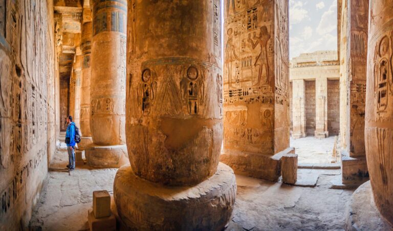 A tourist examines the hieroglyphs on the walls of the temple of Medinet Habu, Luxor, Egypt