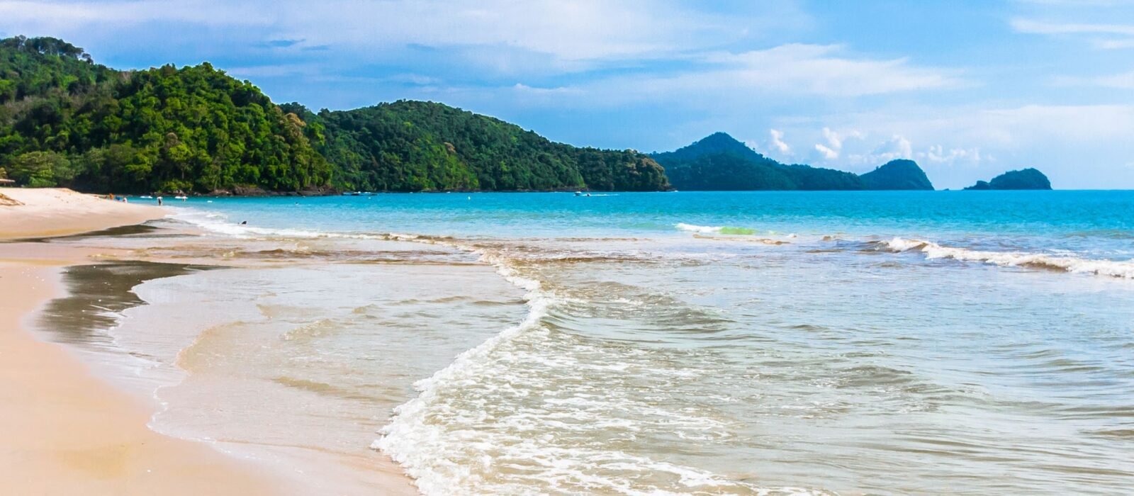 Waves lapping at the golden sands of an empty beach in Langkawi, Malaysia.