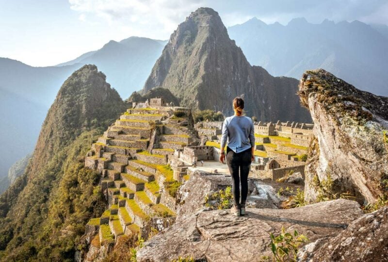 Traveller standing on a rock overlooking Machu Picchu, Peru