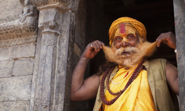 A Varanasi man holding his beard in a doorway