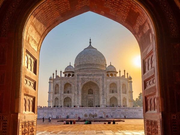 A view of the main domed building of the Taj Mahal through an ornately carved archway