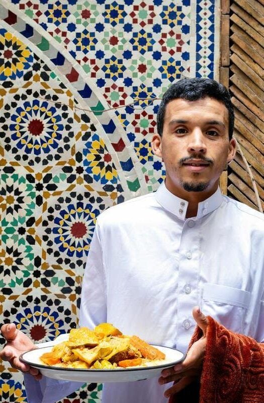 Portrait of a young Berber man holding a vegetarian couscous plate. Marrakesh, Morocco.