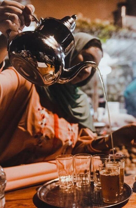 Moroccan woman nigh serving tea at night