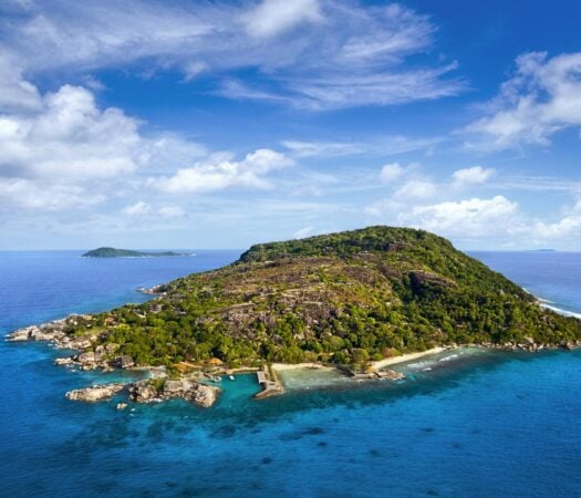 A small island with white beaches, coral reefs, and forests