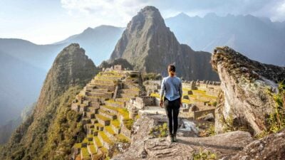 Traveller standing on a rock overlooking Machu Picchu, Peru