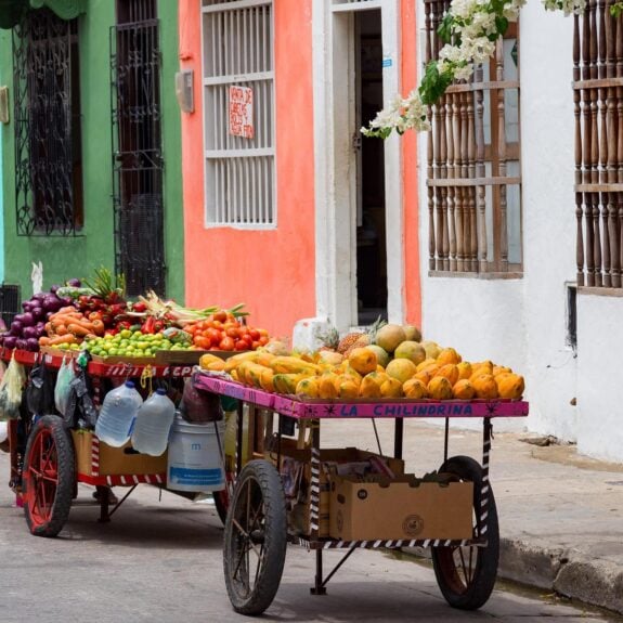 Portable fruit carts on the street by rainbow coloured buildings