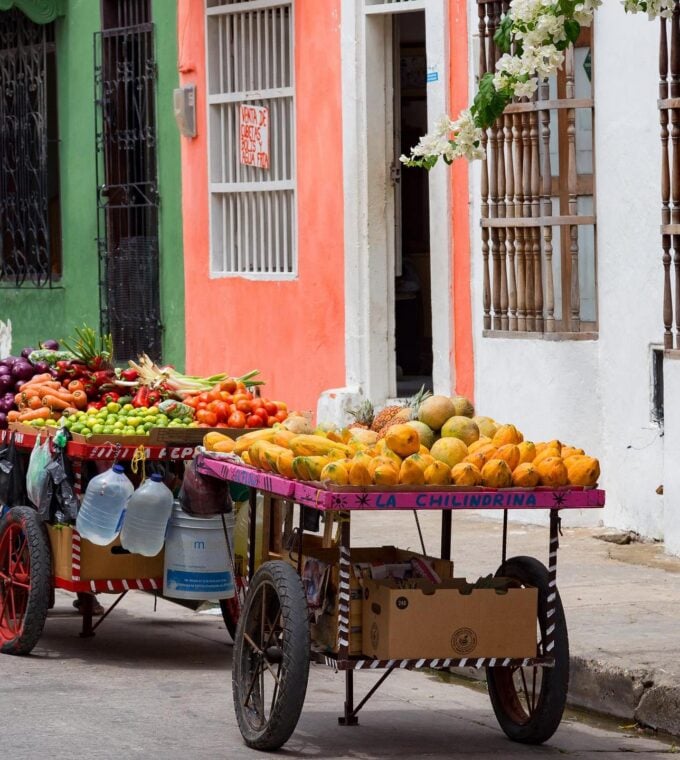 Portable fruit carts on the street by rainbow coloured buildings