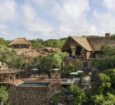 Exterior of Mwiba Lodge, with suites and an outdoor pool with sun loungers and parasols