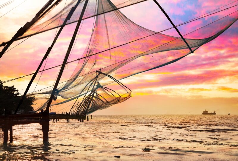 Chinese Fishing nets and small ship at dramatic sunset sky background in Kochi, Kerala, India