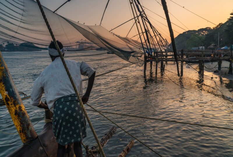 man work at Chinese fishing nets during the Golden Hours at Fort Kochi, Kerala, India