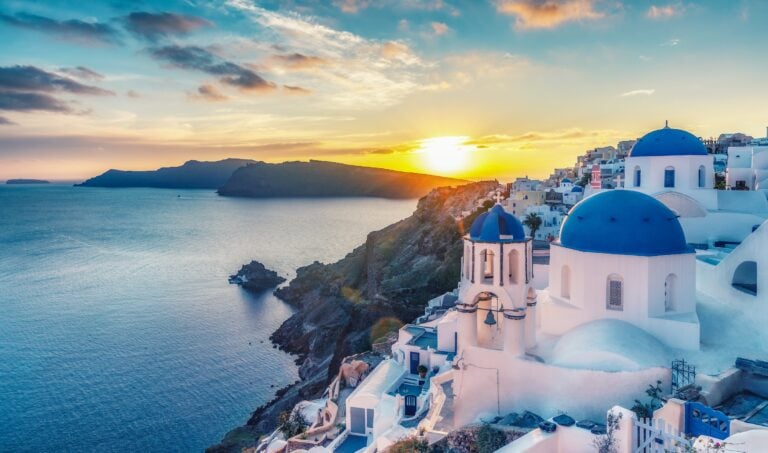 Beautiful view of Churches in Oia village, Santorini island in Greece at sunset, with dramatic sky.