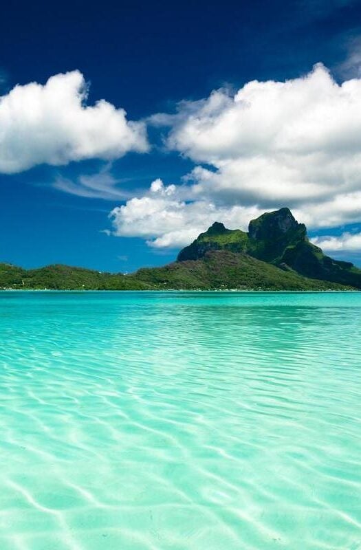 Turquoise water with green mountains in the background in French Polynesia