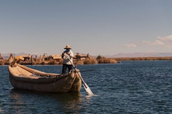 Man paddling a reed boat across Lake Titicaca, Peru